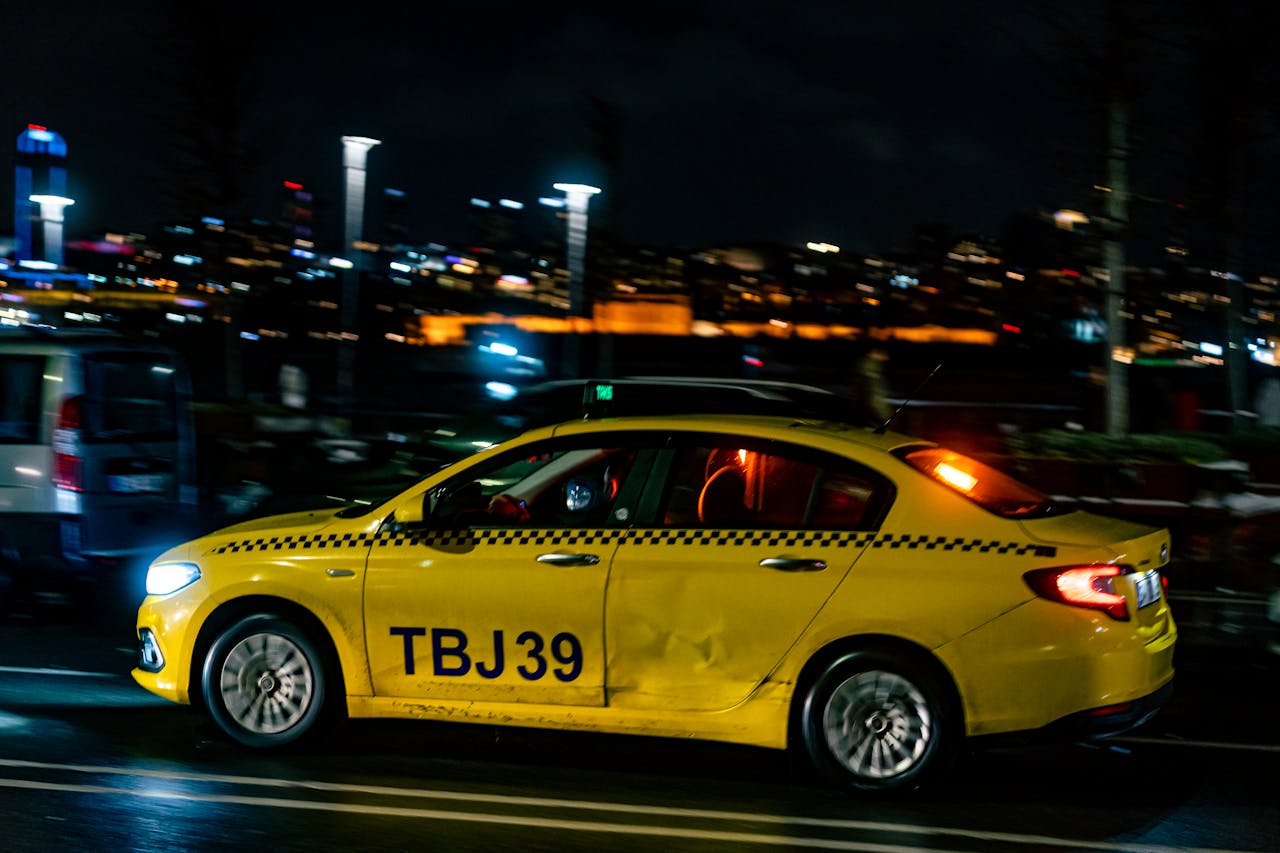 Vivid night street scene with a yellow taxi driving through city streets, showcasing urban nightlife.